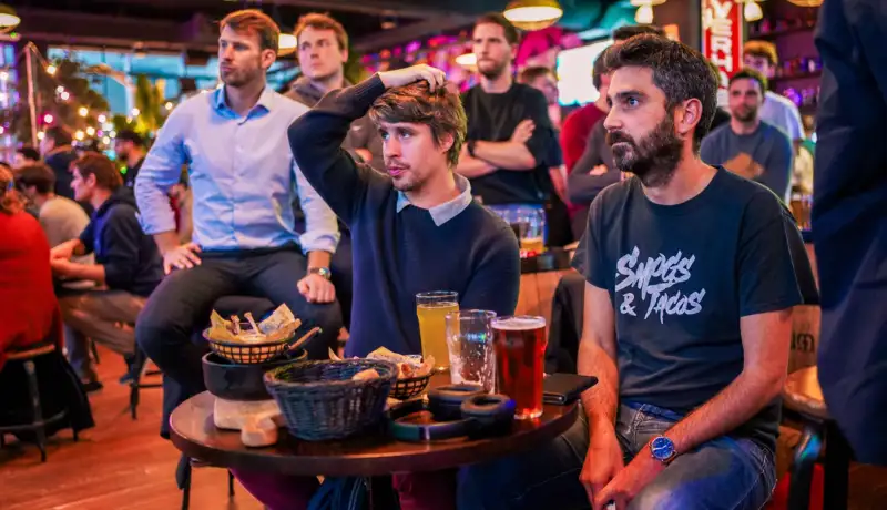 Clients dégustants une planche à partager et regardant le football au Délirium café Bordeaux